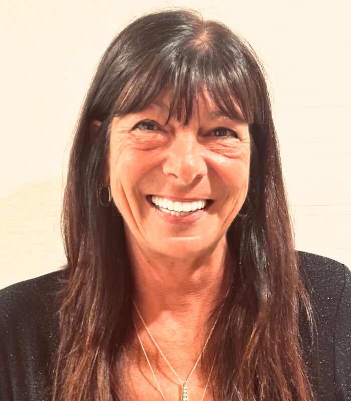Meet Our Team - Professional and Welcoming Group at a Conference Table Faces the Camera, Team Leader Sitting on the Table with Arms Folded